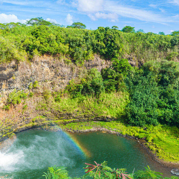 Die majestätischen Wailua-Wasserfälle auf Kauai, Hawaii, umgeben von üppiger grüner Vegetation, stürzen in einen natürlichen Pool