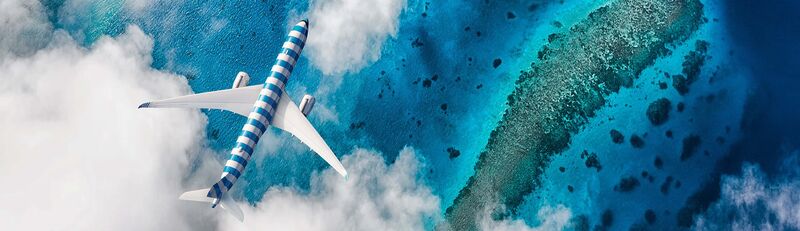 Blick von oben auf ein blau-weiß gestreiftes Flugzeug des Typs A330 neo, das über blaues Meer fliegt.