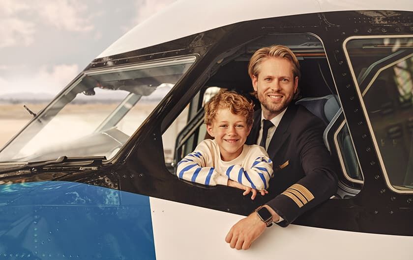 Kapitän mit kleinem Jungen im Cockpit, die aus dem geöffenten Fenster schauen.