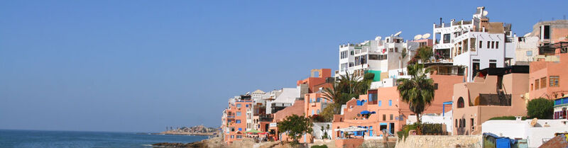 Ein steiler Küstenabschnitt mit Häusern in Agadir, im Hintergrund das Meer