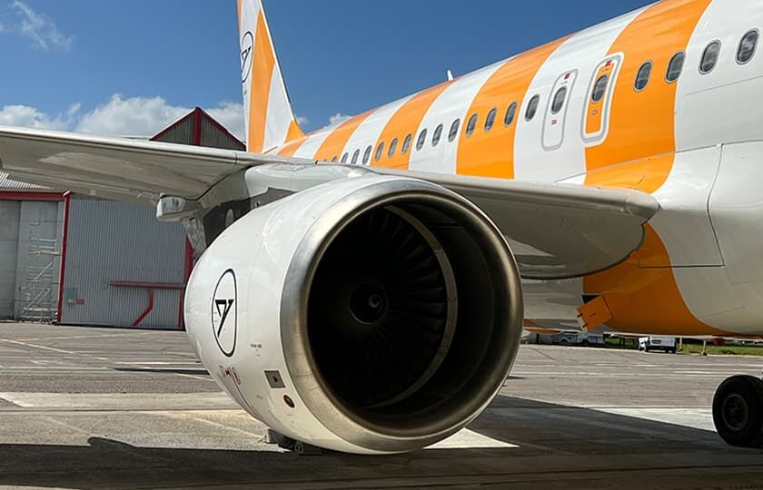 Ausschnitt eines gelbgestreifen Flugzeuges, mit dem Fokus auf einer Turbine