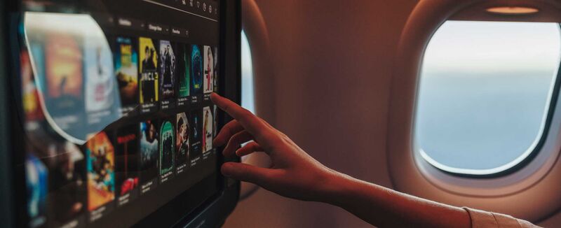 Ein Passagier navigiert auf dem persönlichen Bildschirm durch das Angebot des Condor Unterhaltungsprogramms