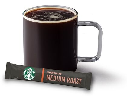 Dunkle Kaffetasse mit Kaffe gefüllt, davor liegend ein Starbucks Asset