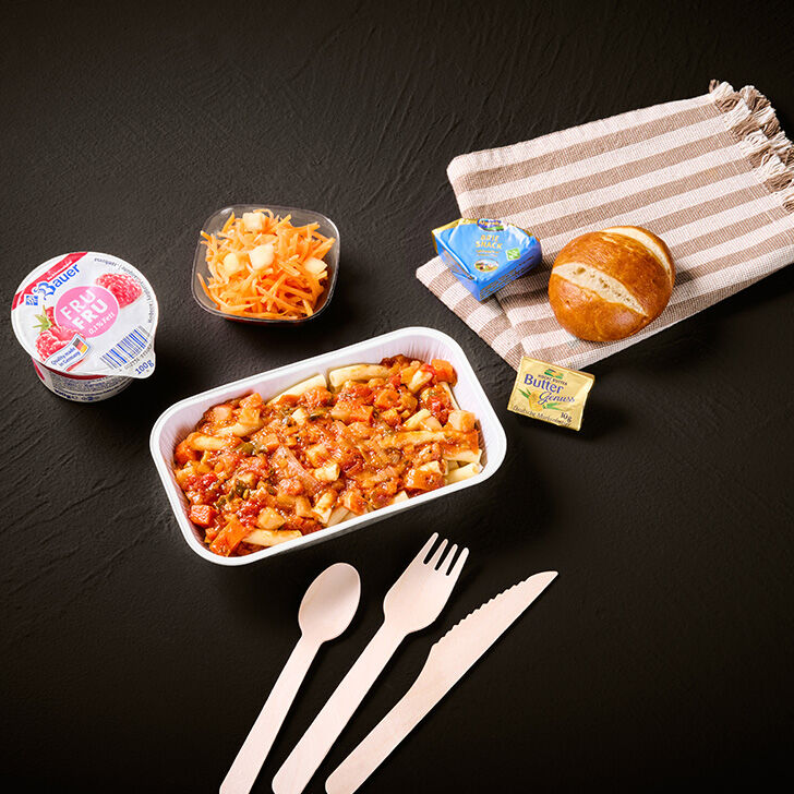 Nudeln in Tomatensauce in einer Aluschale, Kartoffelsalat in einem Plastikbecher, Brötchen, abgepackte Butter und Käse