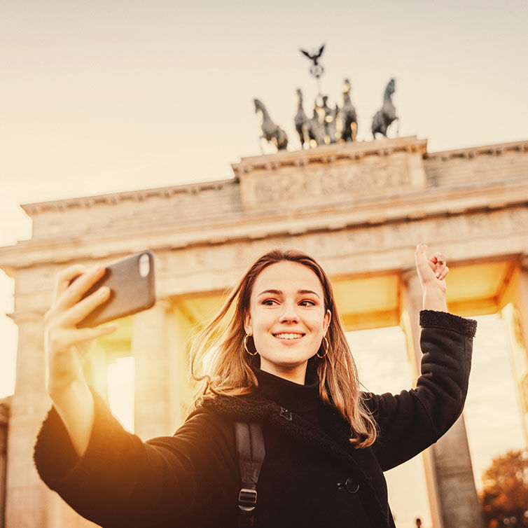 Mujer joven tomándose un selfie frente a la Puerta de Branderburgo