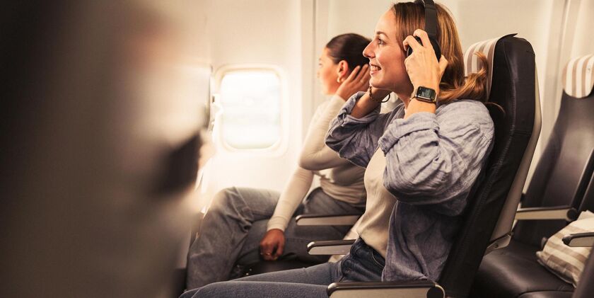 A woman with headphones enjoys the legroom on board