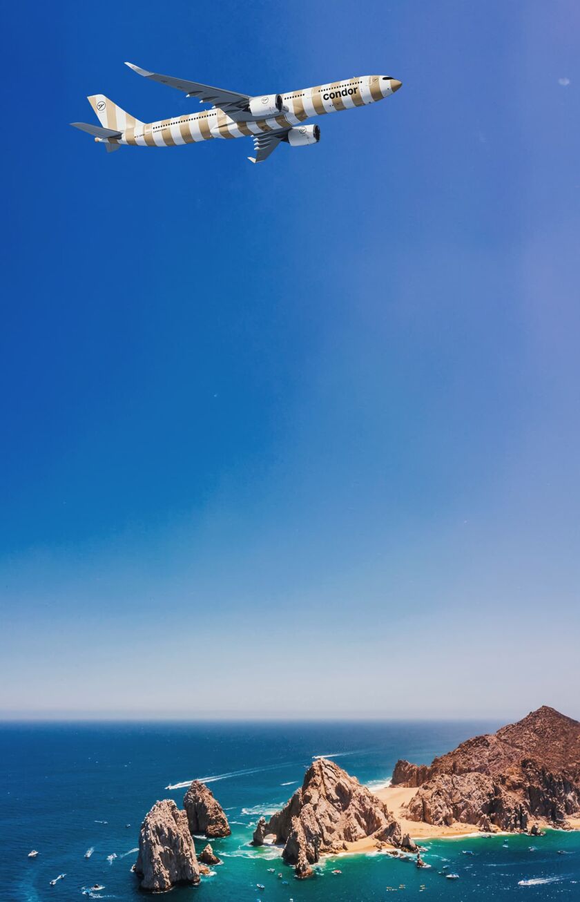 Condor plane flies over a hilly region of Los Cabos