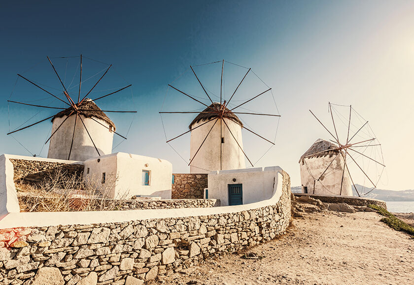 Three whitewashed ancient windmills typical of the Greek island of Mykonos