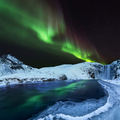 The aurora borealis (Northern Lights) illuminating the night sky with vibrant green hues over a snow-covered landscape 