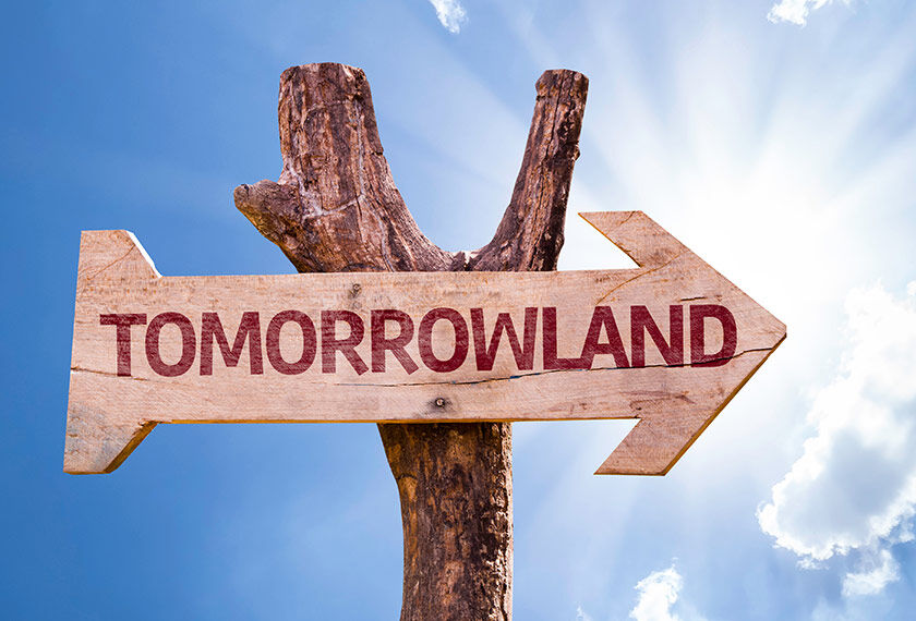 Wooden sign in the shape of an arrow over a blue sky with the word Tomorrowland, indicating the direction to the Tomorrowland music festival.
