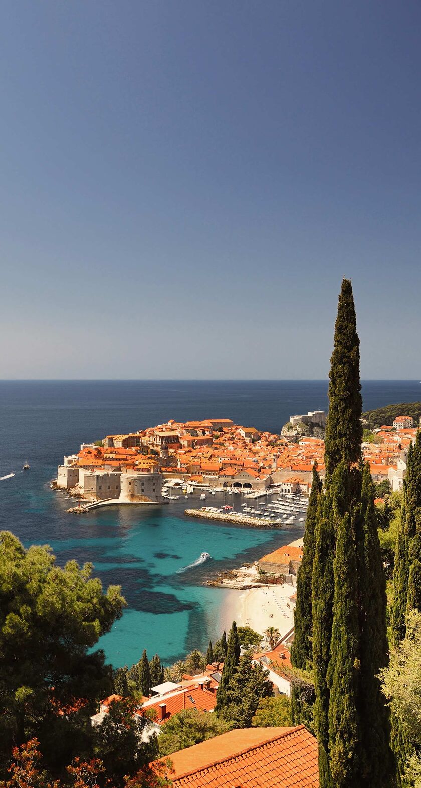 A panoramic view of Dubrovnik, Croatia, with its distinctive orange-roofed buildings surrounded by the Adriatic Sea,