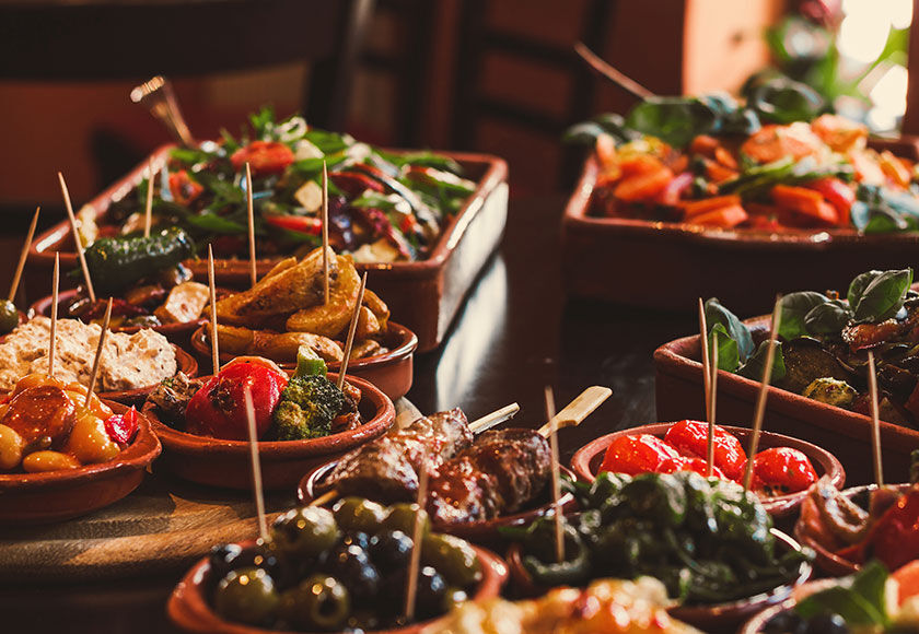 Close-up of a variety of colorful Spanish tapas served on a rustic tray