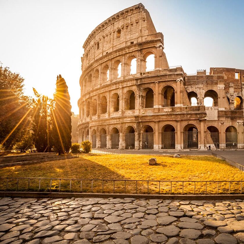 Sun shining through the arches of Coliseum at sunrise, Rome, Italy