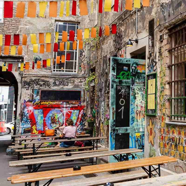  A vibrant urban scene with colorful banners hanging above graffiti-covered walls at Kreuzberg, Berlin.