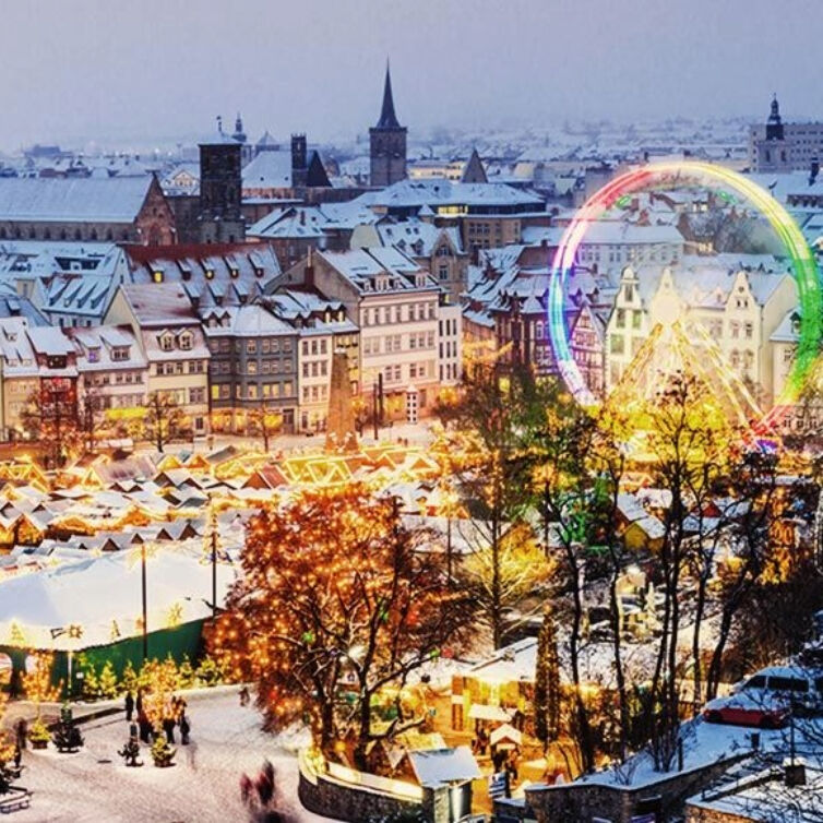 A festive Christmas market in Erfurt, Germany, with snow-covered rooftops and colorful lights,