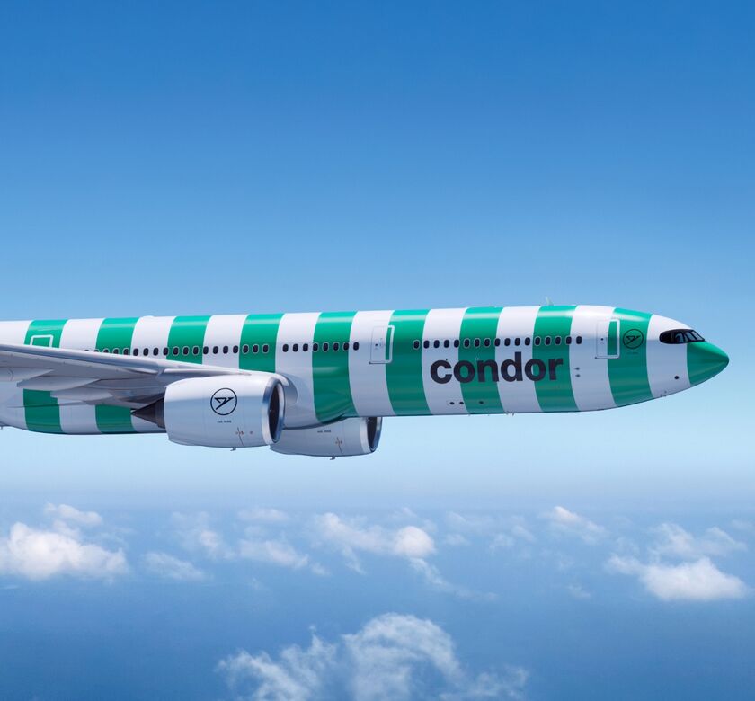 Condor green and white striped livery, in flight against a clear blue sky.