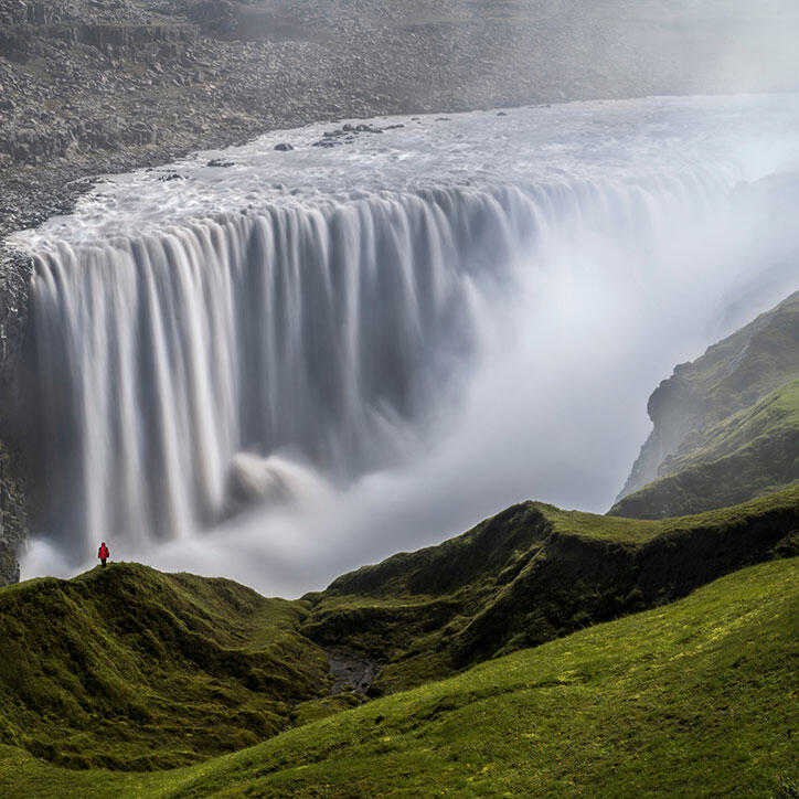 Mensch steht am Wasserfall