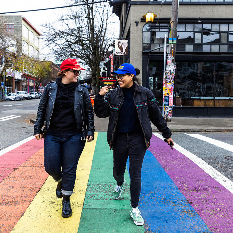 Zwei Frauen überqueren eine Straße in Regenbogenfarben