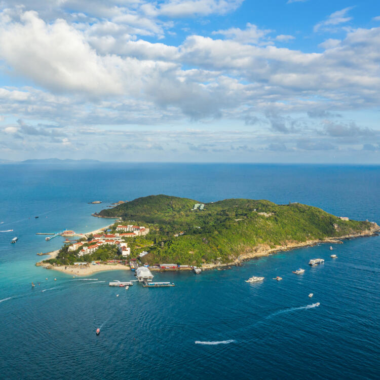 Wuzhizhou Island aus der Vogelperspektive im Meer mit Wolkenhimmel und kleinen Schiffen drumherum