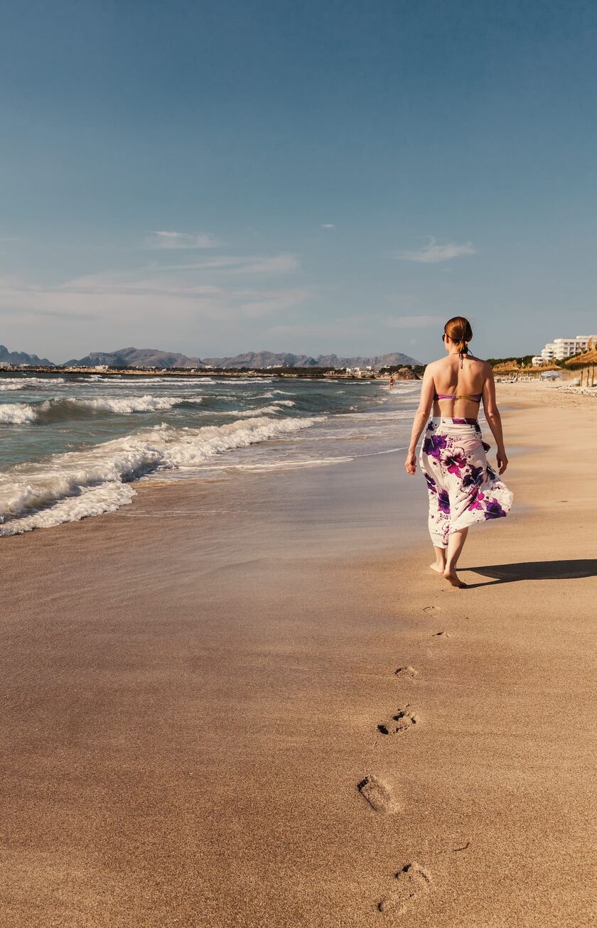 Frau spaziert allein an einem Strand an der spanischen Küste