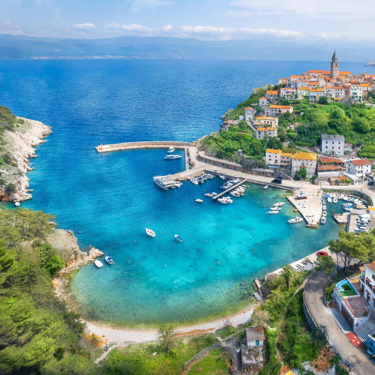 Eine kleine Bucht samt Anlegestellen und Sicht auf die Stadt der Insel Krk