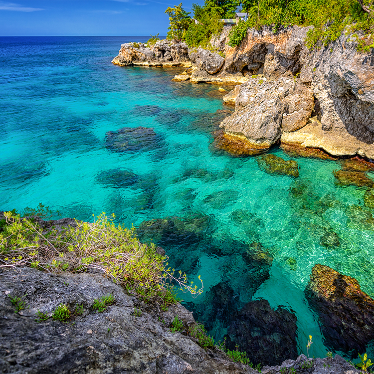 Eine wunderschöne Aussicht auf das klare türkisfarbene Wasser in der Nähe von Felsen und Klippen in Negril, Jamaika