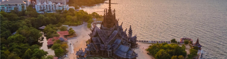 Holztempel in Pattaya Thailand, umgeben von Wasser bei Sonnenuntergang.