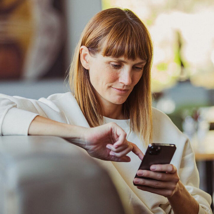 Frau auf der Couch mit Handy in der Hand