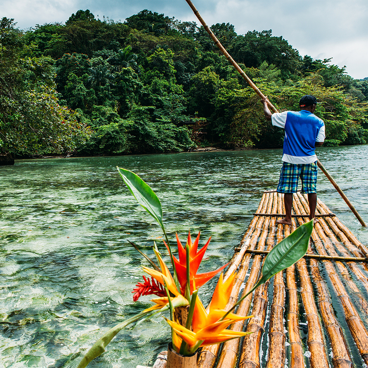 Bambusbootfahrt in der Blue Lagoon auf Jamaika. Der See ist von einer wunderschönen grünen Umgebung umgeben, die aus Bäumen und Pflanzen besteht. Das Wasser ist kristallklar und von türkisblauen Farben