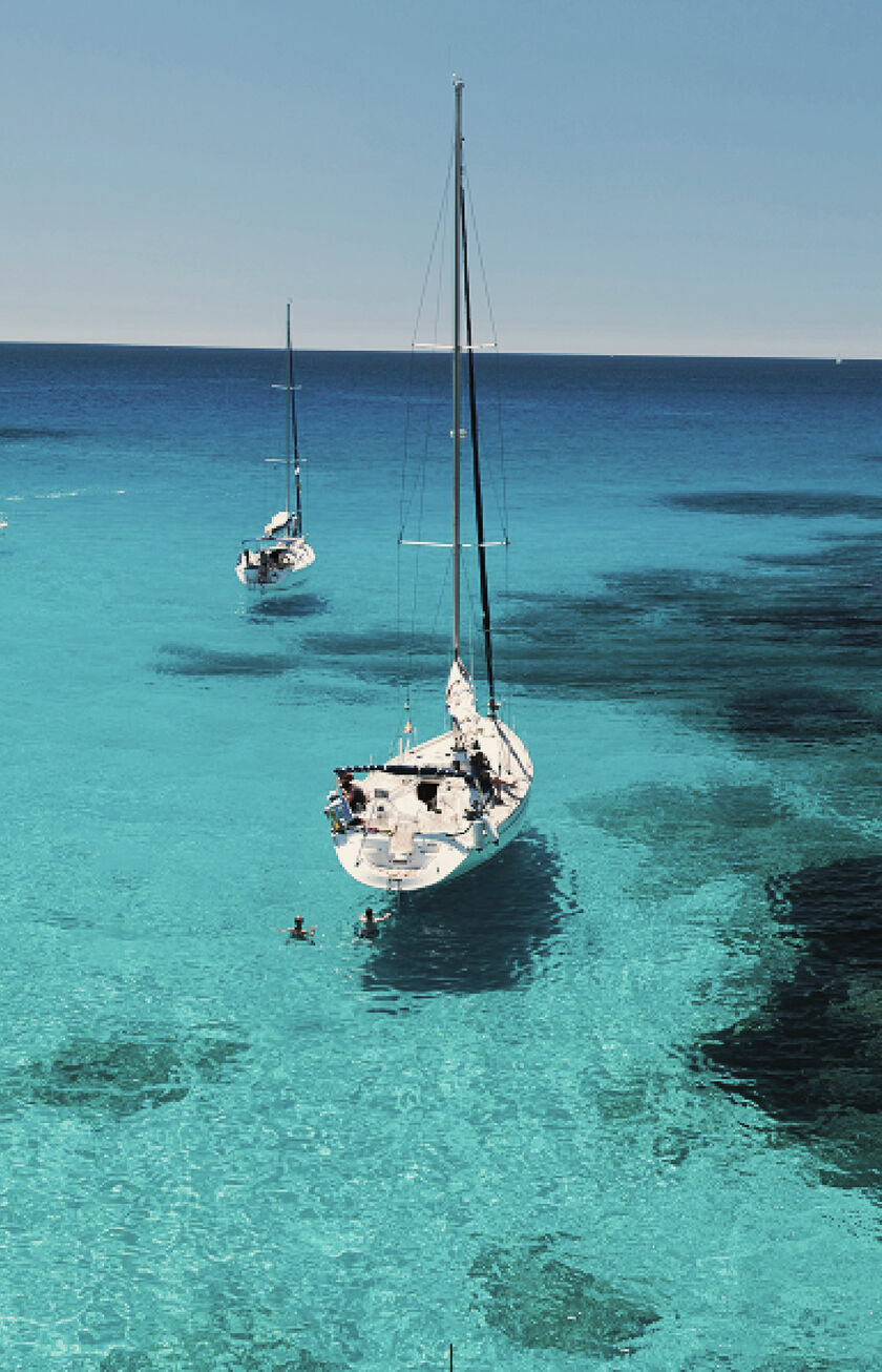 Eine typische türkisblaue Bucht auf Mallorca mit einigen weißen Segelbooten
