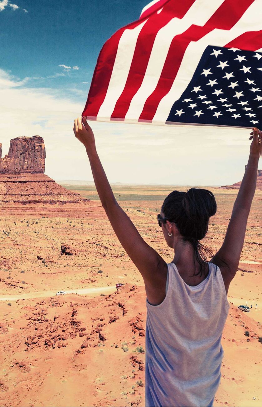 Frau mit der US-Flagge im Monument Valley