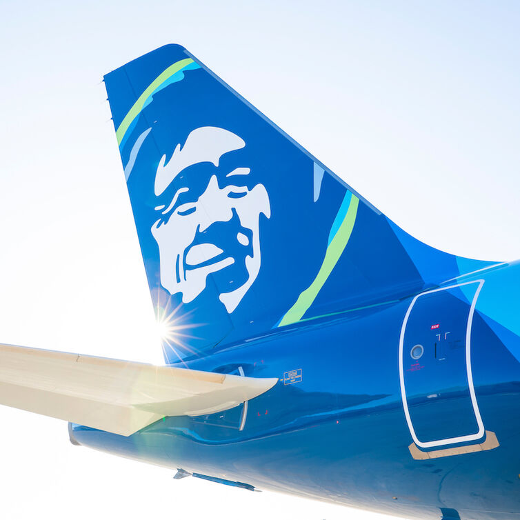 Ocas letadla společnosti Alaska Airlines na pozadí modré oblohy.