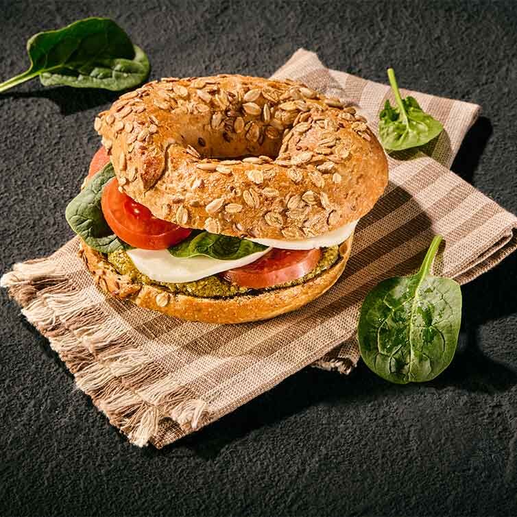 Čerstvý vícezrnný bagel s pesto krémem, mozzarellou a křupavým baby špenátem