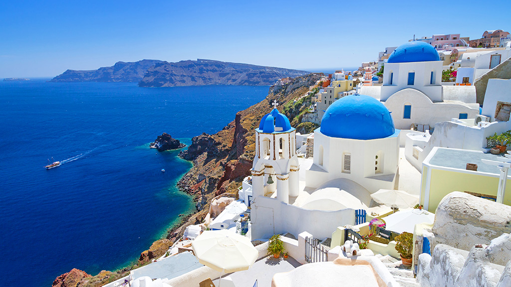 Blick auf Oia und das dunkelblaue Meer in Santorin, weiße Häuser, Felsen im Meer