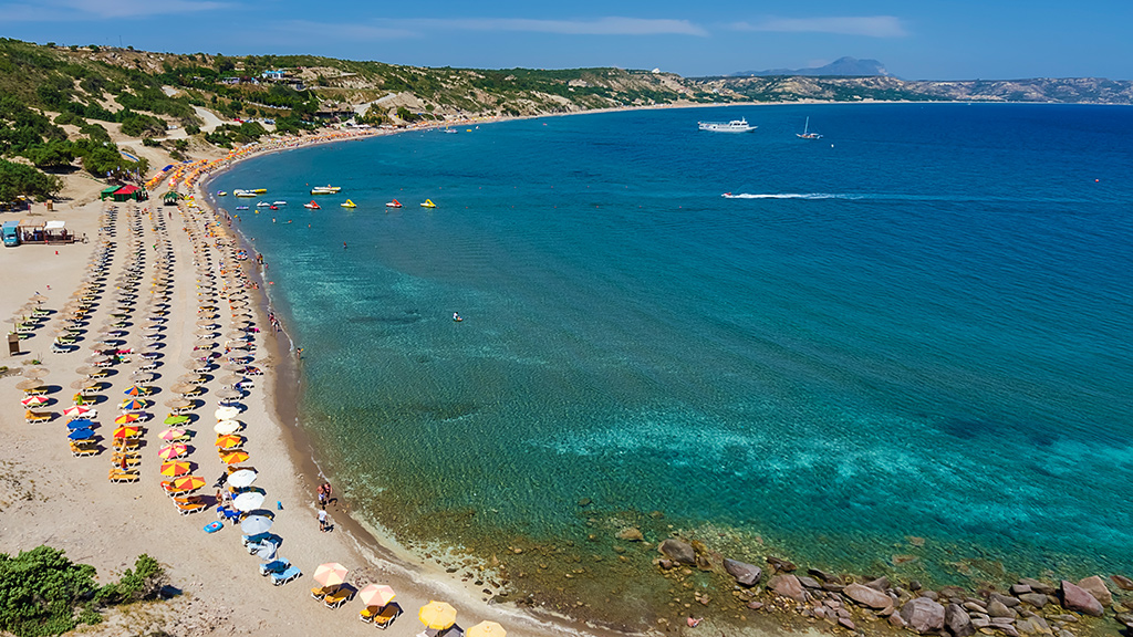 Blick auf Paradise Beach auf Kos, langer Sandstrand mit Liegen und Sonnenschirmen