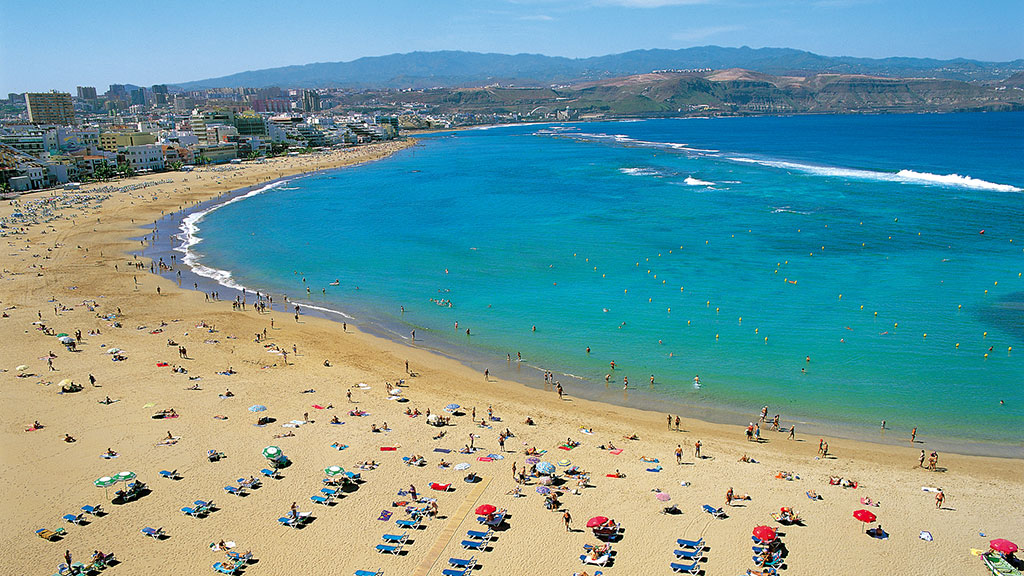 Blick auf langen Sandstrand von Las Canteras auf Gran Canaria mit Sonnenliegen und Menschen am Strand