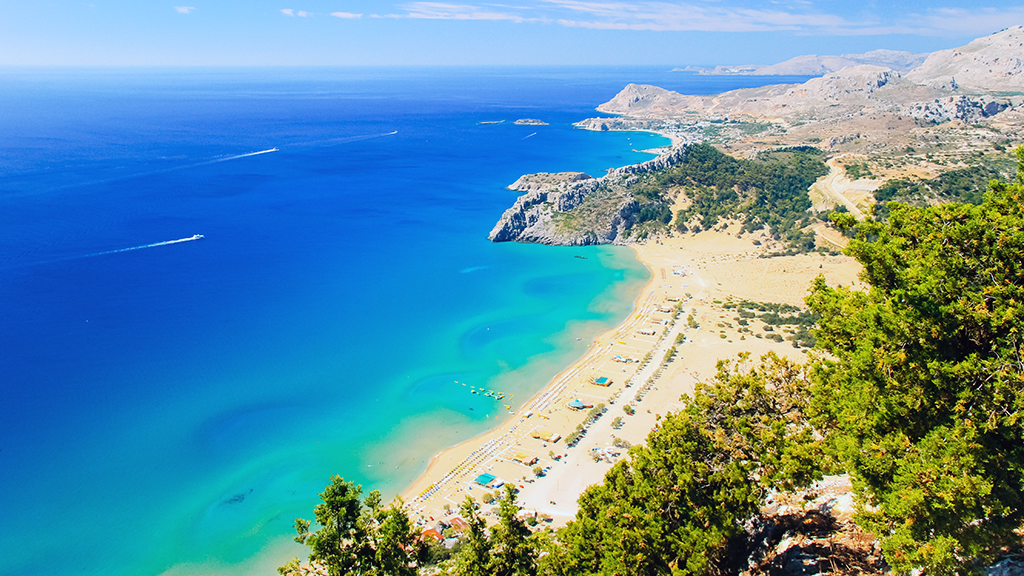 Blick auf Tsambika Beach auf Rhodos, langer Sandstrand, Boote fahren im Meer