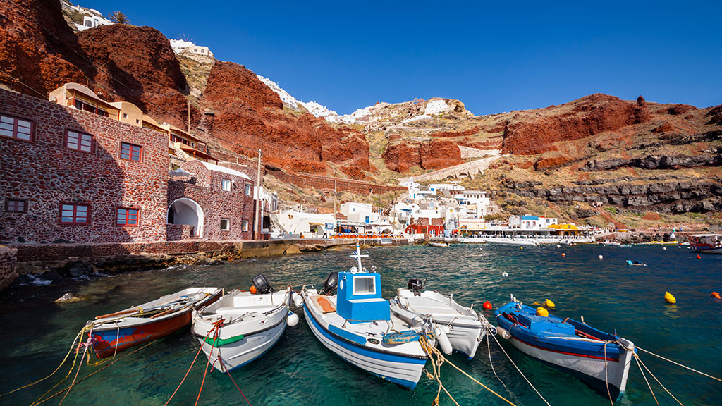 Blick auf Hafen von Ammoudi auf Santorin, rote Felsen, Fischerboote