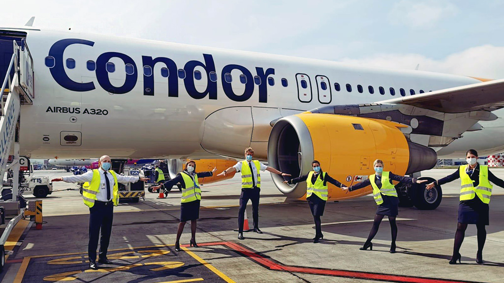 Condor Crew in gelben Warnwesten steht vor Condor Flugzeug