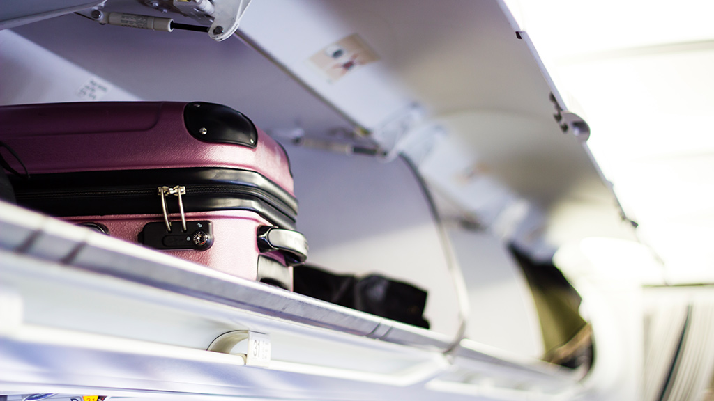 Handgepäck liegt in Gepäckfach in Flugzeugkabine