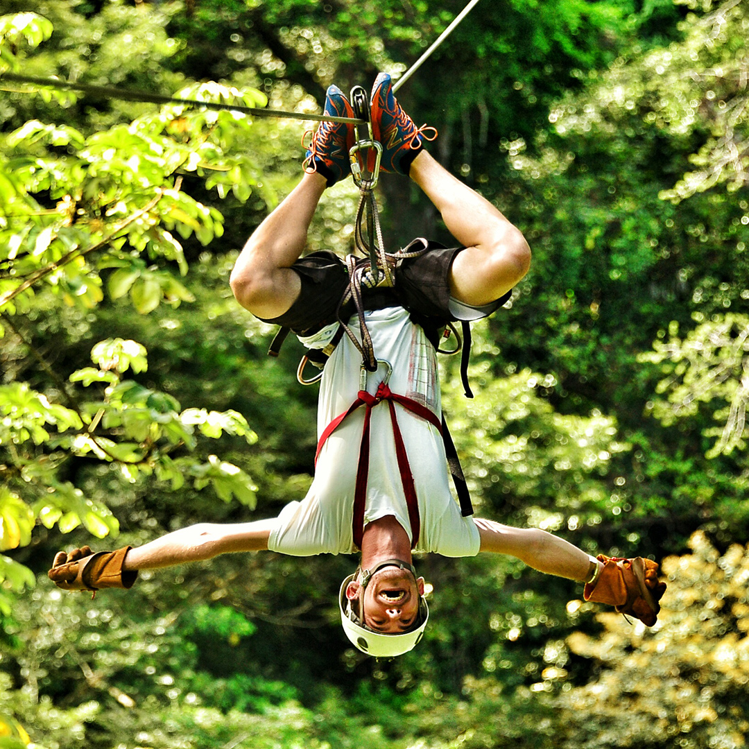 Man hängt kopfüber an Zipline und lacht