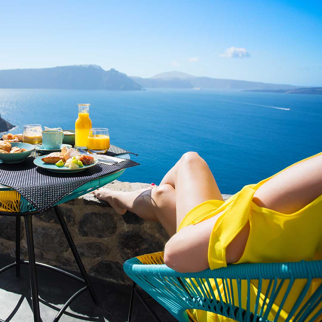 Frau genießt Frühstück auf Santorin mit Blick aufs Meer