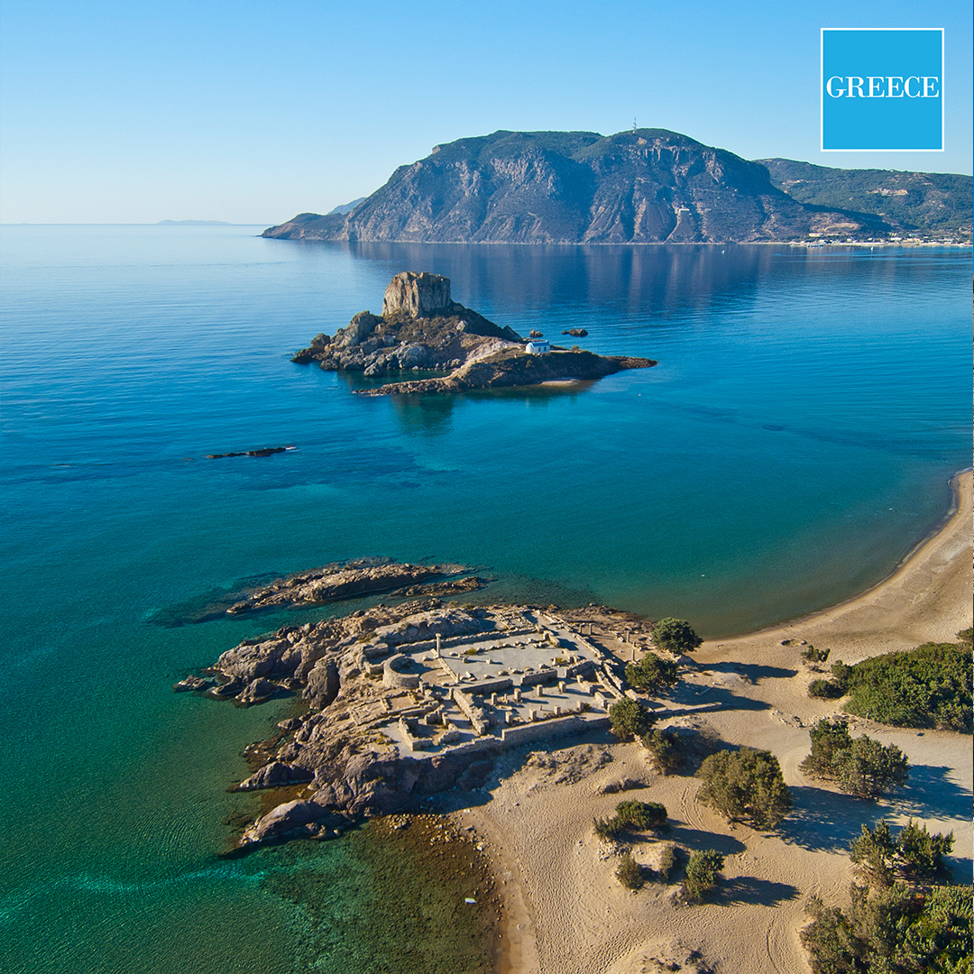 Blick auf Agios Stefanos Beach mit kleiner Insel und Kirche