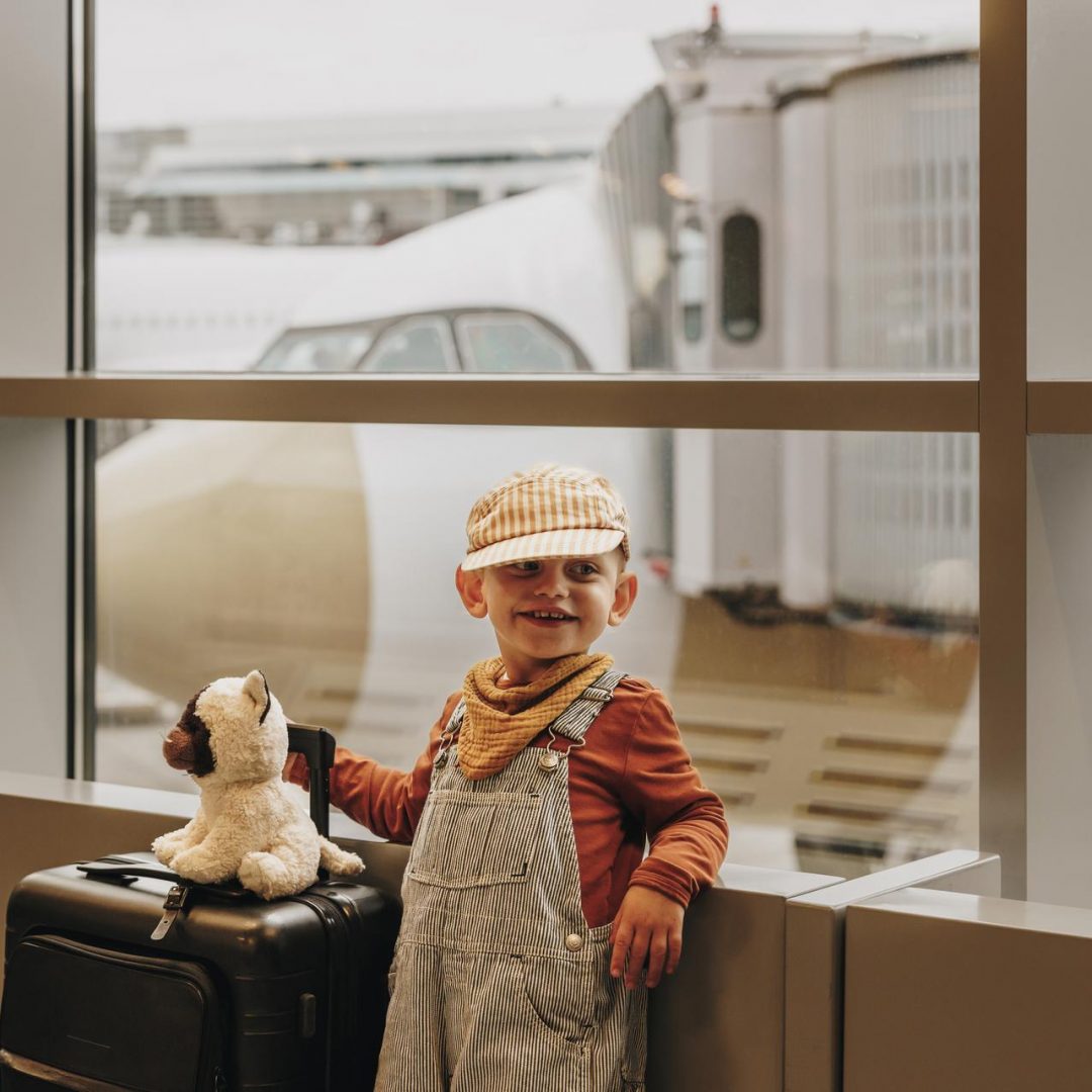 Kleines Kind mit Gepäck am Flughafengate