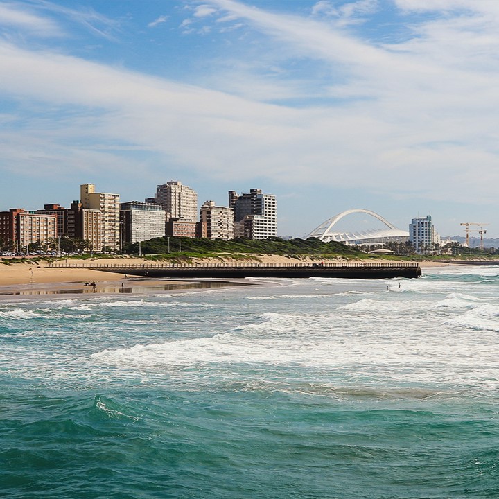 Blick auf Küstenstadt mit modernen Gebäuden und Wellen am Strand.