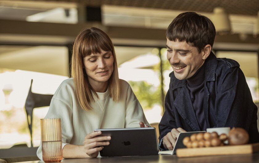 Young Talents | Direkteinstieg Ein paar sitzt am Tisch und schaut auf den Screen eines Tablets