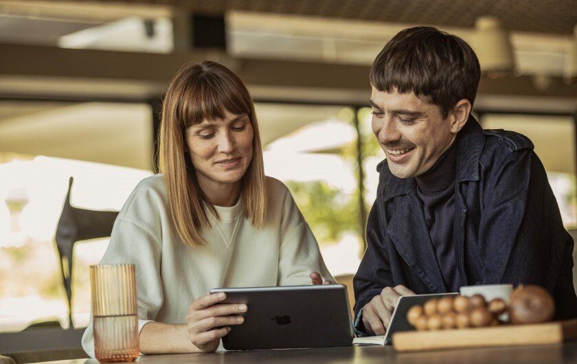 Ein paar sitzt am Tisch und schaut auf den Screen eines Tablets