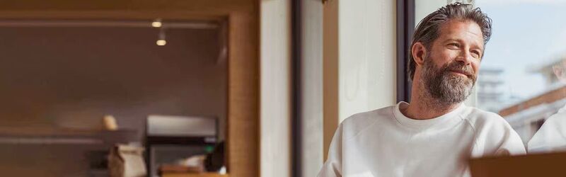 Ein Passagier sitzt in einer hellen Flughafenlounge und liest eine Zeitschrift