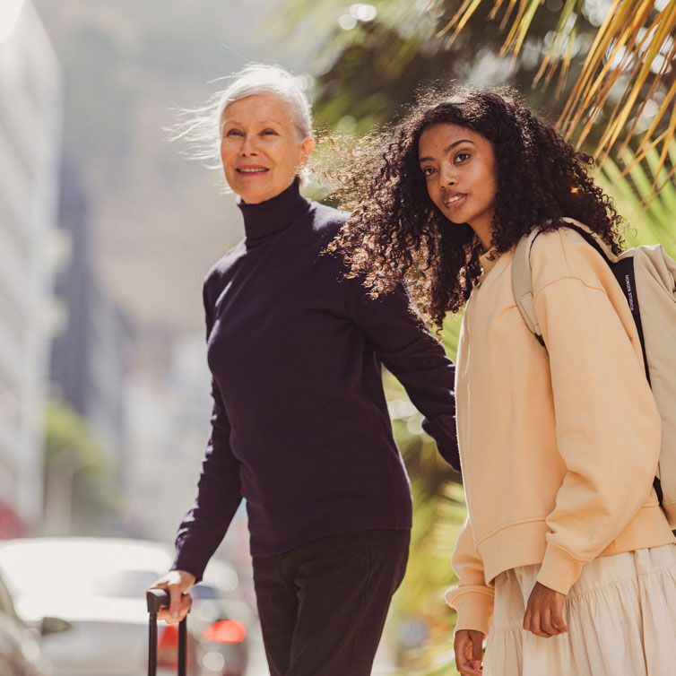 Zwei Frauen mit Gepäck sind auf der Straße unterwegs zu ihrem Airport-Hotel