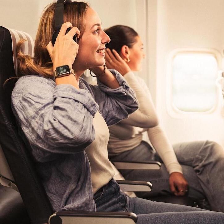 Eine Frau mit Kopfhörer genießt die Beinfreiheit an Bord